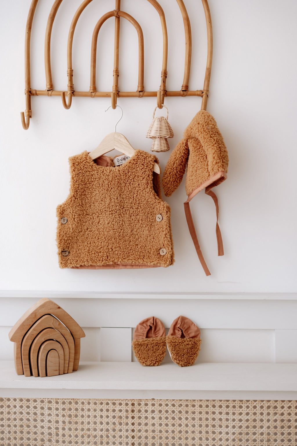 Driedelige teddyset voor baby's in taupe, inclusief vest, muts en anit-slip slofjes, beschikbaar in maten 0-12 maanden en 12-24 maanden.