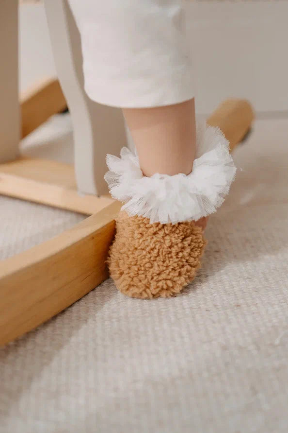 Driedelige teddyset voor baby's in taupe, inclusief vest, muts en anit-slip slofjes, beschikbaar in maten 0-12 maanden en 12-24 maanden.