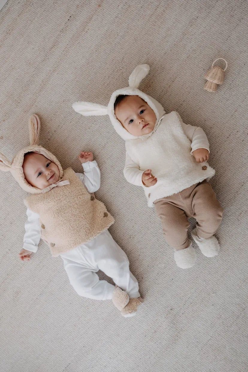 Driedelige teddyset voor baby's in ecru, inclusief vest, muts en anit-slip slofjes, beschikbaar in maten 0-12 maanden en 12-24 maanden.