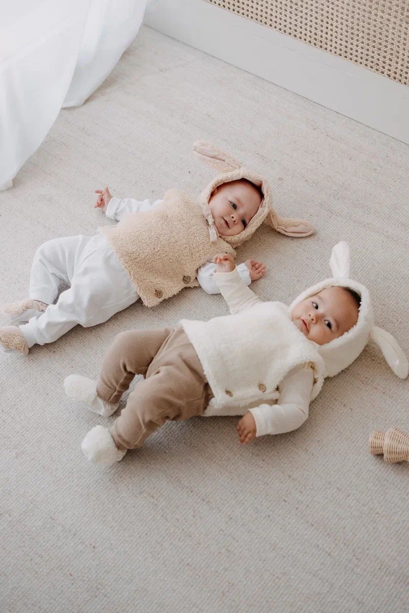 Driedelige teddyset voor baby's in ecru, inclusief vest, muts en anit-slip slofjes, beschikbaar in maten 0-12 maanden en 12-24 maanden.